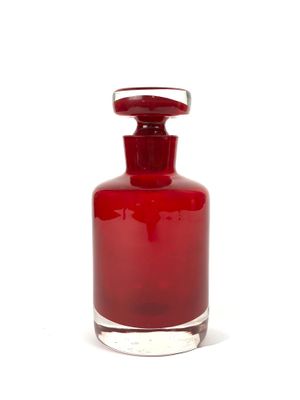 une bouteille en verre rouge avec un bouchon argenté, posée sur une surface blanche