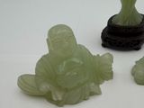 three jade figurines sitting on a white surface