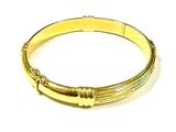 gros plan d'un bracelet en or sur une surface blanche