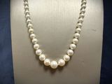 a close up of a necklace with pearls on a mannequin