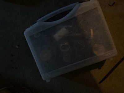 un bac en plastique contenant des vis, posé par terre