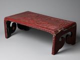 an old red bench sitting on top of a gray floor