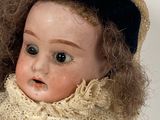 a close up of a doll wearing a hat and scarf