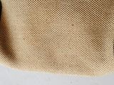 a close up of a tan bag with black handles on a table