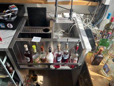 de nombreuses bouteilles d'alcool posées dans un évier en métal