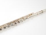 silver flute on a white surface with a white background