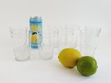 four glasses and a can of soda next to a lemon