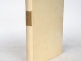un vieux livre à la couverture dorée posé sur une surface blanche