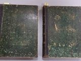 two old books are sitting side by side on a white surface