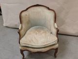 une vieille chaise avec une assise rembourrée blanche devant un fond blanc