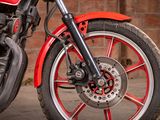 a red and black motorcycle parked next to a brick wall