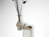 a vase with some flowers in it next to some gold coins