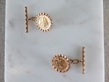 two pairs of gold cufflinks with a coin on a marble surface