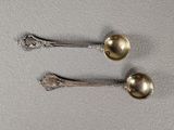 two silver spoons sitting next to each other on top of a table