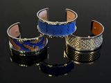 three different colored bracelets on a black surface with reflection