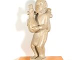 statue d'un homme tenant un oiseau, posée sur un socle jaune