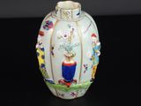 un vase blanc orné de motifs colorés sur un fond noir