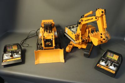 two remote controls and a toy bulldozer on a table