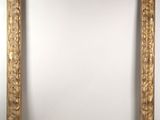 a gold framed mirror on a wall with a white background