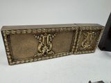 an antique brass plate with ornate design on the front