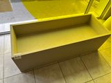 a yellow box sitting on a tiled floor in front of a window