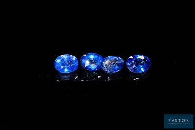 a group of three blue sapphires on a black surface