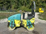 a yellow and blue road roller sitting on top of a gravel road