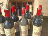 plusieurs bouteilles de vin posées sur une table en bois, à côté d'un sac marron