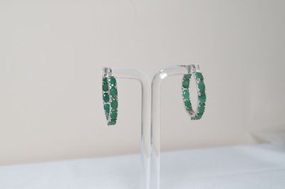 a close up of a pair of green earrings on a stand