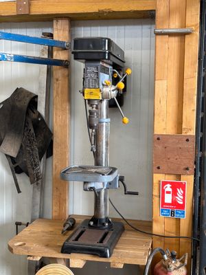 une perceuse à colonne dans un garage, avec un chat assis à côté