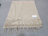 a tan blanket with fringes on it on a bed