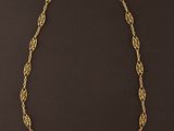 un collier à chaîne dorée orné d'un motif de nœud sur fond noir