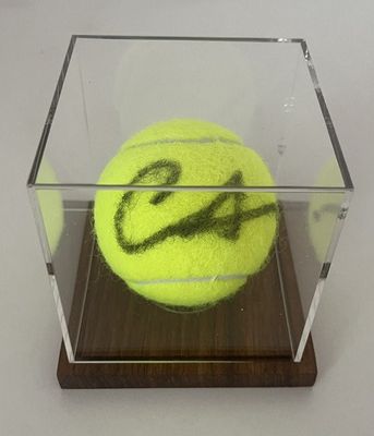 une balle de tennis dans une vitrine sur un socle en bois
