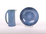 une assiette bleue et un pichet bleu posés l'un à côté de l'autre
