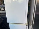 a white refrigerator sitting in a garage next to a trash can