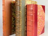 trois vieux livres empilés sur une surface blanche