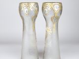 pair of white and gold vases sitting on top of a white table