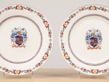 two plates with a coat of arms on them on a table