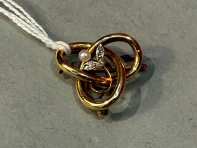 a gold and white necklace with a knot and a pearl