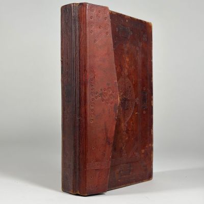 un vieux livre à la couverture brune posé sur une surface blanche
