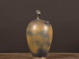 a vase with a bird on top of it on a table