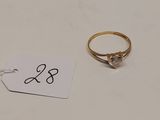 une bague en or sertie d'un diamant, à côté d'une étiquette de prix