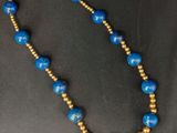 un collier de perles bleues et dorées sur un fond noir