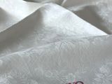 un gros plan d'un lit avec une couette blanche et un t-shirt rouge posé dessus