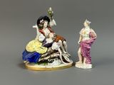 deux figurines représentant des femmes assises sur un rocher, avec des fleurs dans les cheveux