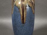 un vase bleu et marron posé sur une surface grise