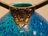 a blue vase with a gold handle on a table