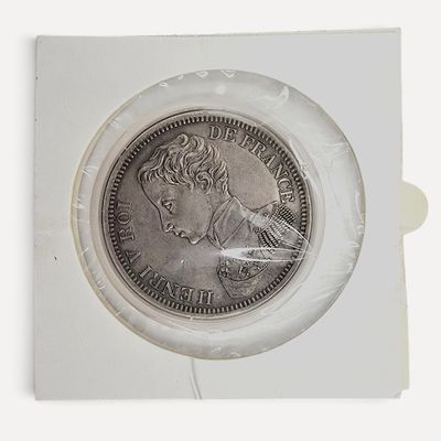 une pièce d'argent dans un étui en plastique posé sur une surface blanche