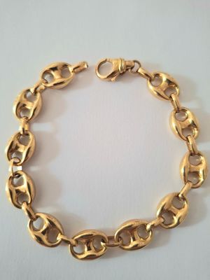 gros plan d'un bracelet en chaîne en or sur une surface blanche