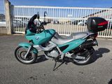 a blue motorcycle parked in a parking lot next to a white fence